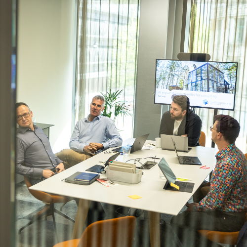ClearBox Consulting team collaborating in a meeting room with laptops and presentation screen showing AI impact opportunities for consulting.