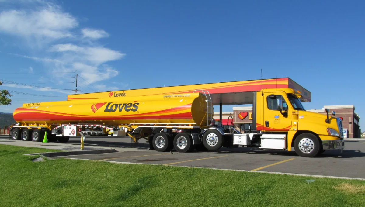 A yellow fuel tanker trick branded as "Love's" in front of a Love's Travel Stop.