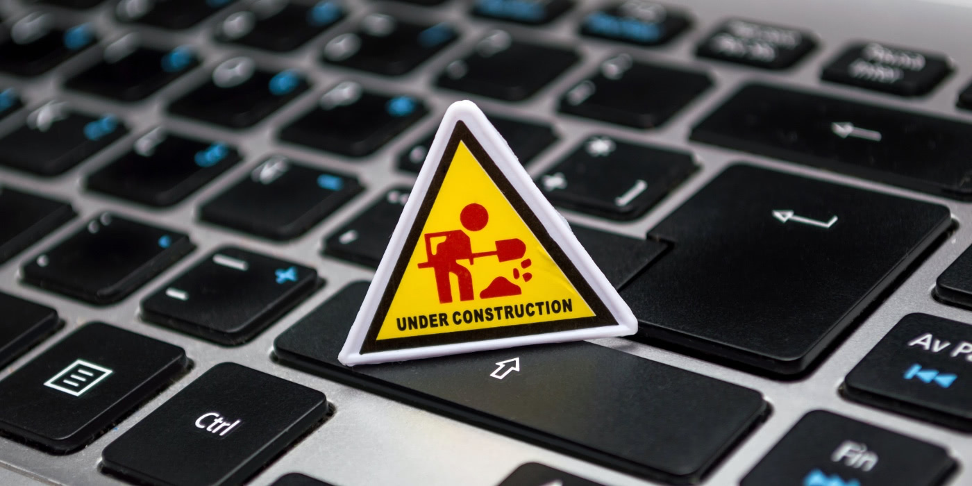 A tiny 'Under construction' road works sign on a laptop keyboard.