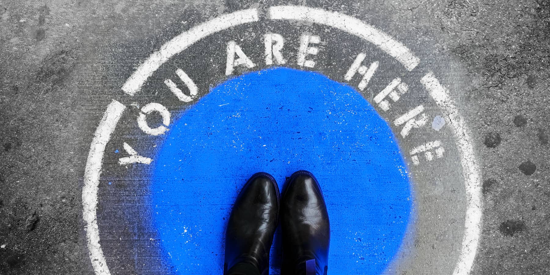 "You are here" stencil spray painted around a blue circle with shoes.